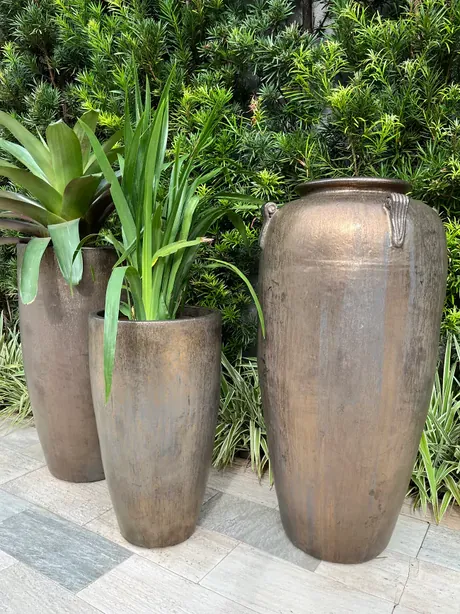 Vasos Portofino acabamento bronze junto a cerca viva