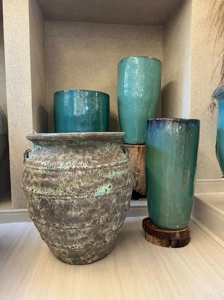 Vasos Portofino claros no jardim, entre árvores